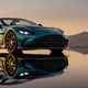 A photo of the front end of an Aston martin V12 Vantage Roadster with mountains behind.